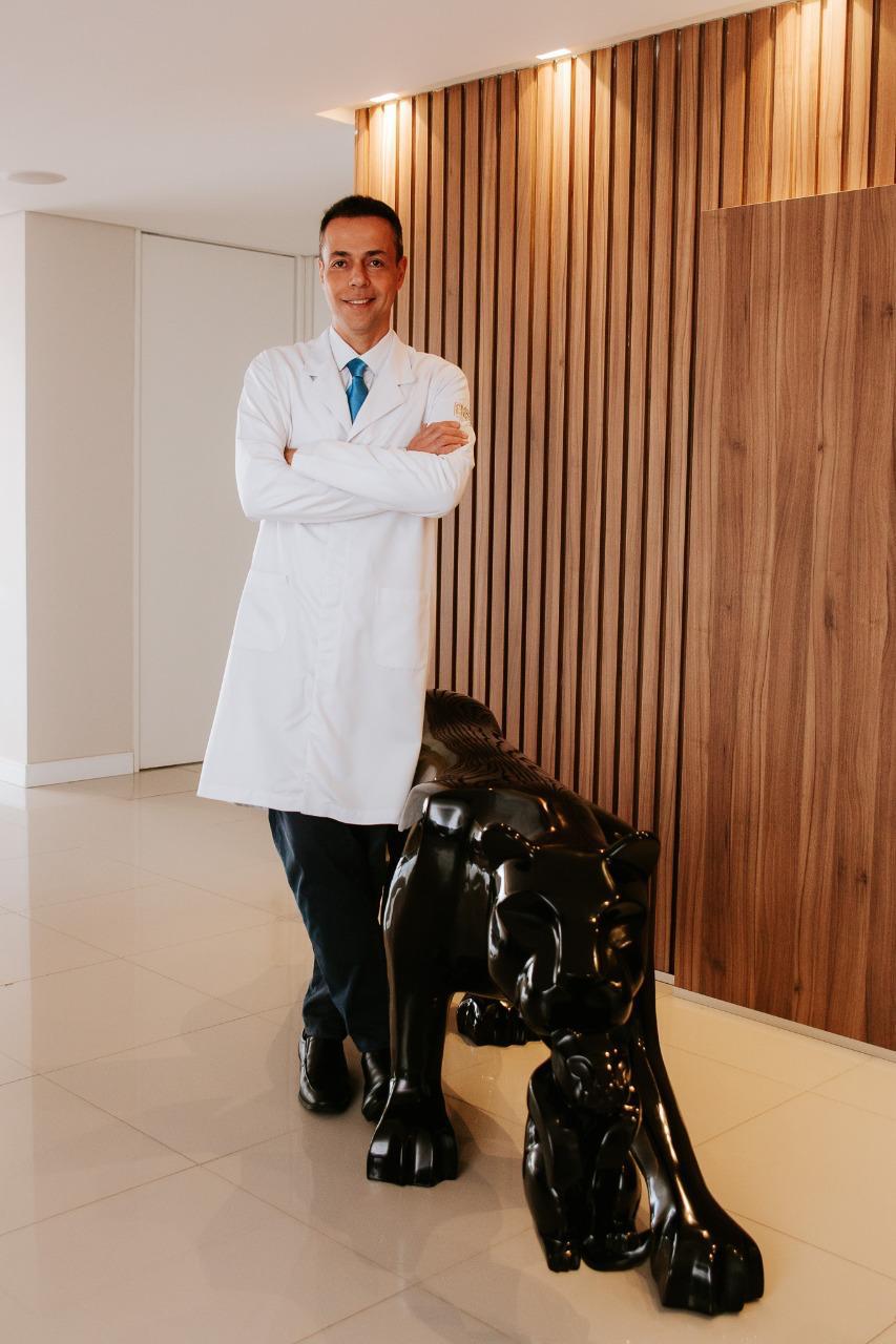 Dr. Wilson em retrato institucional de corpo inteiro, com jaleco branco