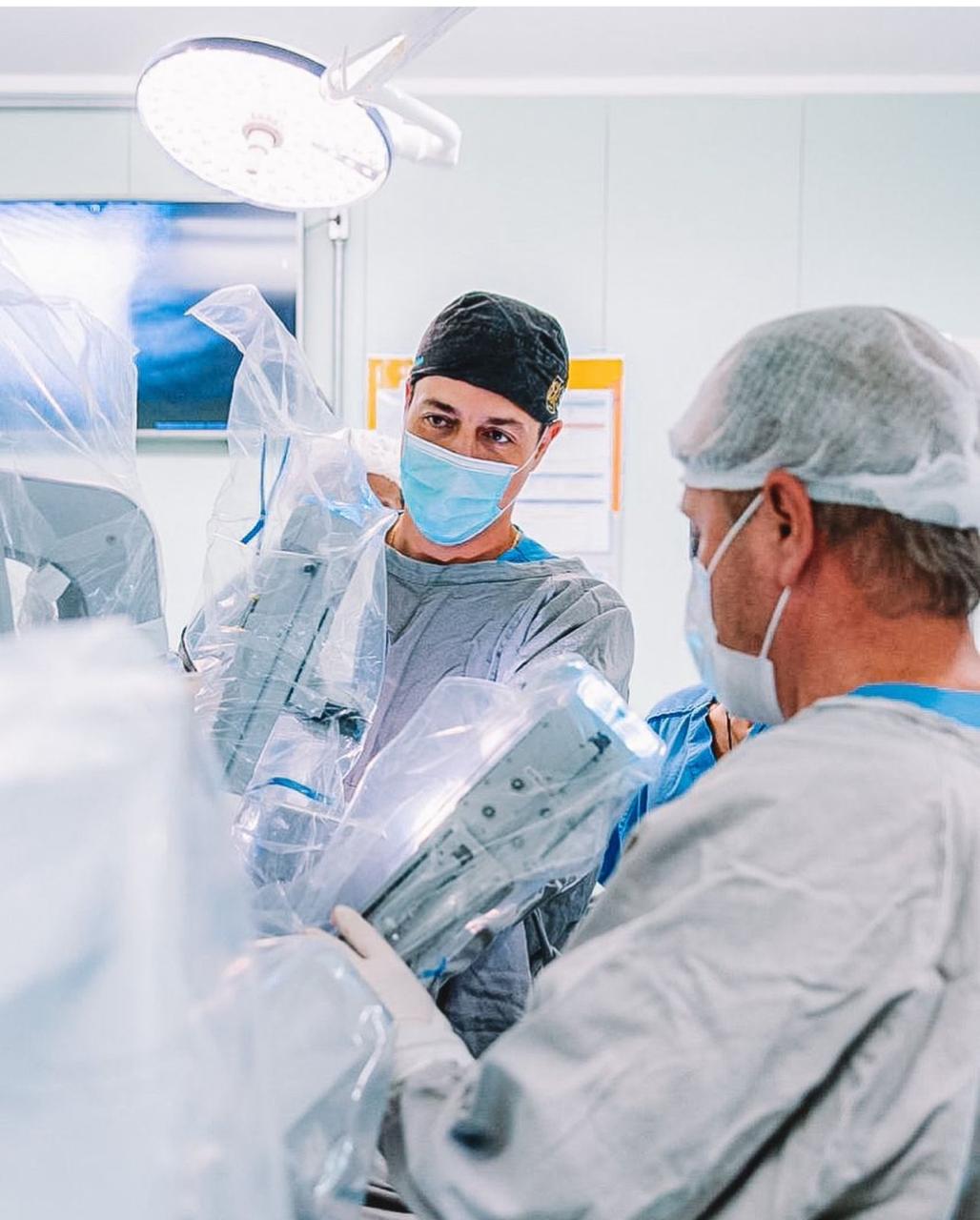 Equipe médica em sala cirúrgica com equipamento de cirurgia robótica